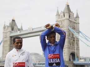 FILE - In this Thursday, April 20, 2017 file photo, Feyisa Lilesa, right, and Kenenisa Bekele from Ethiopia stand in front of the Tower Bridge in London. The Ethiopian marathon runner who made global headlines with an anti-government gesture at the Rio Olympics finish line has returned from exile, after sports officials assured him he will not face prosecution. Feyisa Lilesa's return from the United States on Sunday, Oct. 21, 2018 comes several months after a reformist new prime minister took office and announced sweeping reforms.