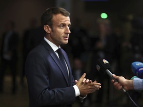 FILE - In this Wednesday, Oct. 17, 2018 file photo, French President Emmanuel Macron speaks with the press as he arrives for an EU summit in Brussels. France's Presidential Press Association has called on President Emmanuel Macron to reconsider his decision to close the press room inside the presidential palace. In a statement Tuesday, Oct, 23 the association that represents French and foreign media accredited with the presidency said the press room's closure would be "a lockdown of the Elysee Palace and a decision prejudicial to journalists' freedom to inform and to work."