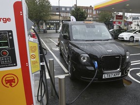 FILE - In this file image dated Wednesday Oct. 18, 2017, 2017, a new TX Cab London taxi is plugged into a charging station in London.  London's black cabs will be seen on the streets of Paris next year as the London Electric Vehicle Company has announced Thursday Oct. 18, 2018, that they will begin selling its wares in the City of Light.