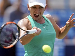 FILE - In this Sunday, Aug. 19, 2018 file photo, Simona Halep, of Romania, returns to Kiki Bertens, of the Netherlands, during the finals at the Western & Southern Open tennis tournament in Mason, Ohio. Halep is back as the year-end No. 1 for the second year in a row despite a back injury that doctors say could lead to a long-term problem. Halep won her first major title at this year's French Open and has had a consistent season but may be forced to pull out of the upcoming Kremlin Cup and the season-ending WTA Finals because of a herniated disk.