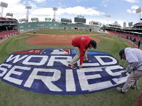 Grounds crew members paint the World Series logo behind home plate at Fenway Park, Sunday, Oct. 21, 2018, in Boston as they prepare for Game 1 of the baseball World Series between the Boston Red Sox and the Los Angeles Dodgers scheduled for Tuesday.