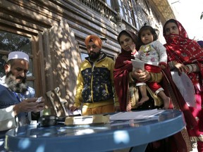 A man and women from the minority Sikh register to vote in Parliamentary elections in old city of Kabul, Afghanistan, Saturday, Oct. 20, 2018. Tens of thousands of Afghan forces fanned out across the country as voting began Saturday in the elections that followed a campaign marred by relentless violence.