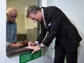Maxime Bernier signs papers as he files the papers for the Peoples Party of Canada at the Elections Canada office in Gatineau, Que., Oct. 10, 2018.