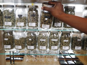 In this Tuesday, Oct. 2, 2018, photo, a clerk reaches for a container of marijuana buds for a customer at Utopia Gardens, a medical marijuana dispensary, in Detroit. Michigan and North Dakota, where voters previously authorized medical marijuana, will decide now if the drug should be legal for any adult 21 and older. They would become the 10th and 11th states to legalize so-called recreational marijuana since 2012.