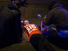 People gather to tend to a protester lying on the ground after a truck collided with into protesters calling for the right to form unions Tuesday, Oct. 2, 2018, in Flint, Mich. Police said the collision appears to be an accident.