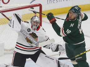 Minnesota Wild's Jordan Greenway, right, gets spun around as Chicago Blackhawks goalie Cam Ward deflects a shot during the first period of an NHL hockey game Thursday, Oct. 11, 2018, in St. Paul, Minn.