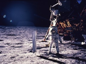 Buzz Aldrin walks on the surface of the moon, with seismographic equipment that he just set up. The flag-like object on a pole is a solar wind experiment and in the background is the Lunar Landing Module. July 20, 1969.