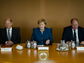German Chancellor Angela Merkel sits between Vice-chancellor and Finance Minister Olaf Scholz, left, Head of Chancellery and Minister for Special Tasks Helge Braun, right, as she leads the weekly cabinet meeting of the German government at the chancellery in Berlin, Wednesday, Oct. 24, 2018.