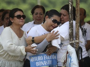 Basilia Bonastre, mother of Arturo Figueroa Bonastre, whose remains were found amid hundreds of others in clandestine graves, is consoled by friends during a Mass in Colinas de Santa Fe, Mexico, Monday, Oct. 15, 2018. The Mass was held one day before the women's Solecito Collective is honored by Notre Dame University for their work locating the remains of missing people in Veracruz state. The Solecito Collective is made up people searching for their missing loved ones.