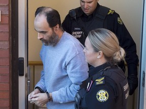 Matthew Vincent Raymond, charged with four counts of first degree murder, is escorted from provincial court in Fredericton on Monday, Oct. 22, 2018.