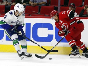 Carolina Hurricanes' Justin Faulk (27) battles with Vancouver Canucks' Brendan Leipsic (9) during the first period of an NHL hockey game, Tuesday, Oct. 9, 2018, in Raleigh, N.C.