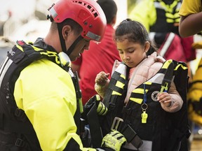 A member of the Winston-Salem Fire Department's water rescue team unzips the life jacket worn by Isabella Molina's, 5, after bringing her from an apartment complex to drier land Thursday, Oct. 11, 2018, after the remnants of Hurricane Michael passed through Winston-Salem, N.C.