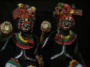 In this Sept. 23, 2018, photo, dancers pose for photographs wearing mask of god Bhot Bhairabh in Kathmandu, Nepal. For centuries, Nepal has celebrated the Indra Jatra festival of masked dancers, which officially begins the month-long festivities in the Hindu-dominated Himalyan nation. The dancers, who come from a variety of backgrounds, pull off this performance every year despite minimal financial support from the government and other sources, they say.