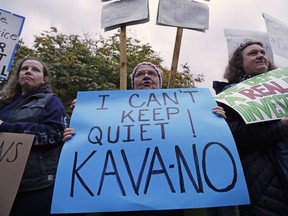 Pam Clark, of Westmoreland, N.H., center, protests outside a political event hosting U.S. Sen. Jeff Flake, R-Arizona, in Manchester, N.H., Monday, Oct. 1, 2018. Flake, days after a critical vote in support of Supreme Court nominee Brett Kavanaugh, made his second visit this year to New Hampshire. The visit will once again stoke suggestions that he might run against President Trump in 2020.