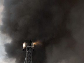 A firefighter atop a crane responds to a seven-alarm fire on Monday, Oct. 22, 2018, in Dover, N.J. The fast-moving blaze ripped through the business district, destroying multiple businesses and causing the partial collapse of at least four buildings, according to officials.
