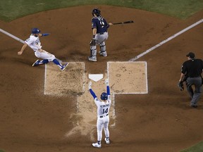 Los Angeles Dodgers' Chris Taylor scores from second on hit by Brian Dozier during the first inning of Game 4 of the National League Championship Series baseball game against the Milwaukee Brewers Tuesday, Oct. 16, 2018, in Los Angeles.