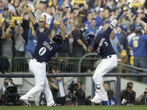 Milwaukee Brewers' Orlando Arcia celebrates his home run with third base coach Ed Sedar during the fifth inning of Game 2 of the National League Championship Series baseball game against the Los Angeles Dodgers Saturday, Oct. 13, 2018, in Milwaukee.