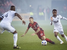 Toronto FC forward Sebastian Giovinco (10) gets tripped up by Vancouver Whitecaps forward Yordi Reyna (29) as Kendall Waston (4) look on during second half MLS soccer action in Toronto on Saturday, Oct. 6, 2018.