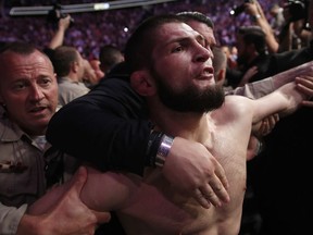 Khabib Nurmagomedov is held back outside of the cage after fighting Conor McGregor in a lightweight title mixed martial arts bout at UFC 229 in Las Vegas, Saturday, Oct. 6, 2018. Nurmagomedov won the fight by submission during the fourth round to retain the title.