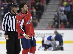 FILE - In this Sept. 30, 2018, file photo, Washington Capitals right wing Tom Wilson (43) is escorted by an official off the ice after he checked St. Louis Blues center Oskar Sundqvist, on ice at back center, during the second period of an NHL preseason hockey game, in Washington. Wilson has been suspended 20 games by the NHL for a blindside hit to the head of an opponent during a preseason game. Wilson's punishment was announced Wednesday, Oct. 3, 2018, just hours before the reigning Stanley Cup champion Capitals were to raise their banner and open their title defense by hosting the Boston Bruins to begin the regular season.