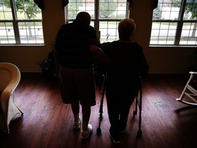 FILE - In this June 30, 2017 file photo, an elderly couple walks inside an assisted living facility in Illinois. According to a study released on Monday, Oct. 1, 2081, a bone-strengthening drug given intravenously every 18 months greatly lowered the risk of fracture in certain older women. The results suggest these drugs may benefit more people than those who get them now and that they remain effective when used less often.