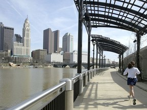 FILE - In this March 15, 2004, file photo, a woman runs the Franklinton floodwall next to the Scioto River in Columbus, Ohio. The largest city named for Christopher Columbus has called off its observance of the holiday named for the explorer. Offices in Columbus, Ohio, will remain open Monday, Oct. 8, 2018, and close on Veterans Day instead.