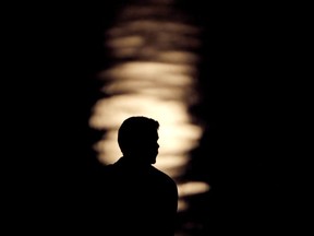 FILE- In this June 27, 2018, file photo a man is silhouetted against moonlight reflecting off the Missouri River as he watches the full moon rise beyond downtown buildings in Kansas City, Mo. A by the Associated Press-NORC Center for Public Affairs Research and MTV found that half of 15 to 26-year olds think they will eventually be better off than their parents in terms of household finances. About 29 percent expect to do as well as their parents and 20 percent expect to be worse off.