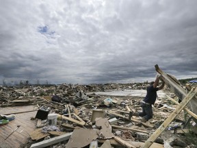 FILE - In this April 30, 2014, file photo, Dustin Shaw lifts debris as he searches through what is left of his sister's house at Parkwood Meadows neighborhood after a tornado in Vilonia, Ark. A new study finds that tornado activity is generally shifting eastward to areas just east of the Mississippi River that are more vulnerable such as Mississippi, Arkansas and Tennessee. And it's going down in Oklahoma, Kansas and Texas.