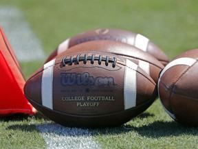 FILE - In this Sept. 2, 2017, file photo, footballs sit on the turf ready for kick-off before the start of an NCAA football game between South Carolina and North Carolina State in Charlotte, N.C. A study from The Institute for Diversity and Ethics (TIDES) finds that white men still "overwhelmingly" fill leadership positions at top-level college sports programs and conferences, leaving a "consistent underrepresentation of women and people of color" in those roles.