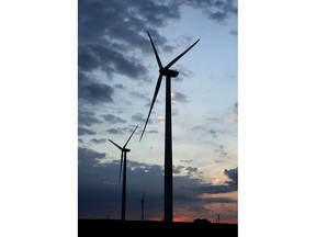 FILE - In this June 1, 2017 file photo, wind turbines, which are part of the Lost Creek Wind Farm, stand against the sky at dusk near King City, Mo.  A new study out of Harvard finds that ramping up wind power in America would also dial up the nation's temperatures.