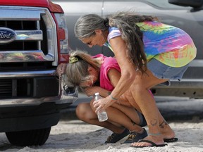 FILE - In this Oct. 17, 2018 file photo Nancy Register weeps as she is comforted by Roxie Cline, right, after she lost her home and all the contents inside to Hurricane Michael in Mexico Beach, Fla.  The tropical weather that turned into monster Hurricane Michael began as a relatively humble storm before rapidly blossoming into the most powerful cyclone ever to hit the Florida Panhandle, causing wrenching scenes of widespread destruction.