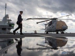 A crew member walks the fly deck of the HMS Queen Elizabeth, Britain's largest warship, during a visit near the Lower New York Bay, Saturday, Oct. 20, 2018, in New York.