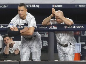 New York Yankees' Giancarlo Stanton, left, and Brett Gardner watch play from the dugout during the seventh inning of Game 4 of baseball's American League Division Series against the Boston Red Sox, Tuesday, Oct. 9, 2018, in New York.