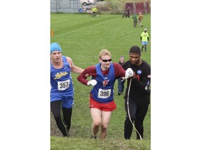 In this Saturday, Oct. 13, 2018 photo provided by Karen Wylie, Cazenovia High School sophomore Jake Tobin, left, helps Fairport High School senior Luke Fortner, center, during a cross country race in Auburn, N.Y. Fortner, who is legally blind, fell towards the end of the race but was assisted by Tobin, and Jerry Thompson, right, his running aide. The three then crossed the finish line together.
