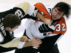 FILE - In this Tuesday, Oct. 14, 2008, file photo, Pittsburgh Penguins' Eric Godard, left, and Philadelphia Flyers' Riley Cote (32) fight in the first period of an NHL hockey game in Pittsburgh. As Cote took and delivered countless punches over more than a decade of junior and pro hockey, he was eager to avoid painkillers. Now a handful of years into retirement, Cote is a proponent of cannabis and its oils as an alternative to more addictive drugs commonly used by athletes to play through pain.
