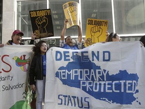 FILE - In this Monday, March 12, 2018, file photo, supporters of temporary protected status immigrants hold signs and cheer at a rally before a news conference announcing a lawsuit against the Trump administration over its decision to end a program that lets immigrants live and work legally in the United States outside of a federal courthouse in San Francisco. A judge on Wednesday, Oct. 3, 2018, blocked the Trump administration from ending protections that let immigrants from four countries live and work legally in the United States, saying the move would cause "irreparable harm and great hardship."