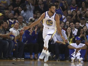 Golden State Warriors' Stephen Curry celebrates after scoring against the Phoenix Suns during the first half of a preseason NBA basketball game Monday, Oct. 8, 2018, in Oakland, Calif.