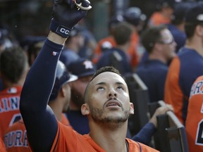 Houston Astros' Carlos Correa celebrates in the dugout after hitting a three-run home run in the eighth inning during Game 3 of a baseball American League Division Series against the Cleveland Indians, Monday, Oct. 8, 2018, in Cleveland. Marwin Gonzalez and Yuli Gurriel scored on the play.