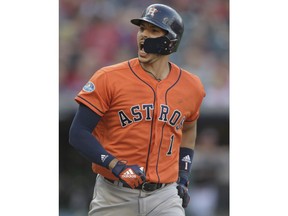 Houston Astros' Carlos Correa looks at the dugout as he runs the bases after hitting a three-run home run in the eighth inning during Game 3 of a baseball American League Division Series against the Cleveland Indians, Monday, Oct. 8, 2018, in Cleveland. Marwin Gonzalez and Yuli Gurriel scored on the play.