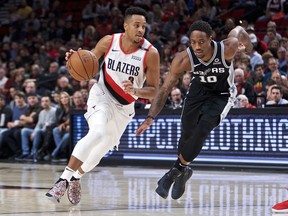 Portland Trail Blazers guard CJ McCollum, left, dribbles past San Antonio Spurs guard DeMar DeRozan during the first half of an NBA basketball game in Portland, Ore., Saturday, Oct. 20, 2018.