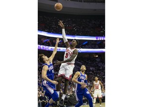 Chicago Bulls Bobby Portis, center, takes the shot as he splits between Philadelphia 76ers Dario Saric, left, of Croatia, and Ben Simmons, right, of Australia, during the first half of an NBA basketball game, Thursday, Oct. 18, 2018, in Philadelphia.