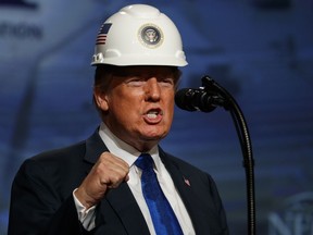 President Donald Trump pumps his fist after putting on a hard hat given to him before speaking to the National Electrical Contractors Association Convention at the Pennsylvania Convention Center, Tuesday, Oct. 2, 2018, in Philadelphia.