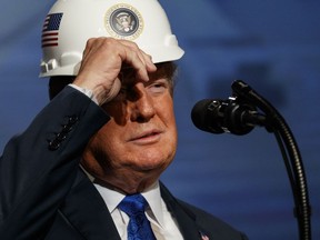 President Donald Trump puts on a hard hat given to him before speaking to the National Electrical Contractors Association Convention at the Pennsylvania Convention Center, Tuesday, Oct. 2, 2018, in Philadelphia.