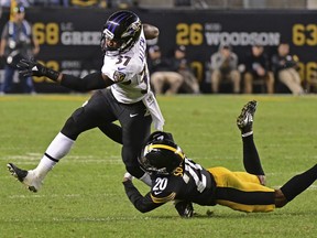 Baltimore Ravens running back Javorius Allen (37) slips the tackle by Pittsburgh Steelers cornerback Cameron Sutton (20) during the second half of an NFL football game in Pittsburgh, Sunday, Sept. 30, 2018.