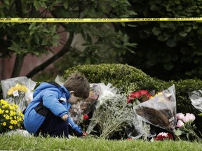 Gideon Murphy places a flower at the Tree of Life Synagogue in Pittsburgh, Sunday, Oct. 28, 2018. Robert Bowers, the suspect in Saturday's mass shooting at the synagogue, expressed hatred of Jews during the rampage and told officers afterward that Jews were committing genocide and he wanted them all to die, according to charging documents made public Sunday.