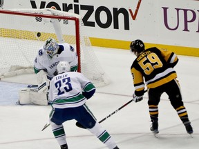 Pittsburgh Penguins' Jake Guentzel (59) scores on Vancouver Canucks goaltender Anders Nilsson, left, during the first period of an NHL hockey game, Tuesday, Oct. 16, 2018, in Pittsburgh.