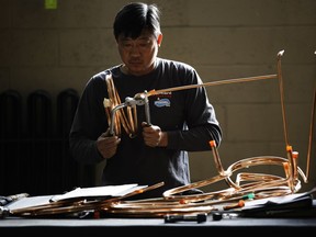 In this Thursday, Oct. 18, 2018, photo Minh Pham bends tubing at the Howard McCray's commercial refrigeration manufacturing facility in Philadelphia.  The experience Christopher Scott, president of Howard McCray, has had suggests that the impact of the tariffs is still playing out. Though has absorbed the higher costs for now, he hopes to eventually pass some on to his customers. First, though, he wants to see how his larger competitors handle the higher costs. "Little Howard McCray can't go out and raise prices 10 percent and lose all the market share that we've worked so hard to gain," Scott said.