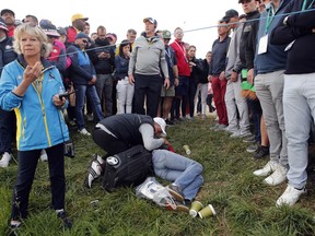 FILE - In this Friday, Sept. 28, 2018 file photo a man tends an unidentified injured woman after she was hit by US player Brooks Koepka's ball on the 6th hole during a fourball match on the opening day of the 42nd Ryder Cup at Le Golf National in Saint-Quentin-en-Yvelines, outside Paris, France. Ryder Cup organizers say they are alarmed by the news that a spectator hit by a Brooks Koepka's tee shot at the Ryder Cup says she has lost sight in her right eye.