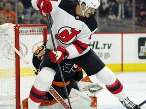 The loose puck is knocked away by Philadelphia Flyers goalie Brian Elliott, rear, as New Jersey Devils' Brian Boyle tries to control it during the first period of an NHL hockey game, Saturday, Oct. 20, 2018, in Philadelphia.