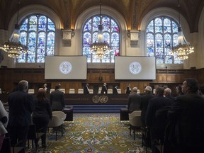 The delegations of the U.S., front left, and the Islamic Republic of Iran, front right, rise as judges, rear, enter the International Court of Justice, or World Court, in The Hague, Netherlands, Wednesday, Oct. 3, 2018, to rule on an Iranian request to order Washington to suspend sanctions against Tehran.